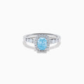The Lab Grown Blue and White Diamond Halo Ring in 14K White Gold showcases a rectangular light blue center stone, surrounded by lab grown diamonds and accented with diamonds along the band for added sparkle.