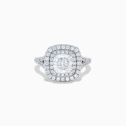 The Lab Grown Cushion Diamond Double Halo Ring in 14K White Gold features a cushion-cut center diamond, double halo of smaller diamonds, and additional diamonds along the band.