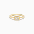 The Lab Grown Diamond East West Emerald-Cut Ring in 14K Yellow Gold features a lab diamond in a minimalist bezel setting, beautifully crafted and shown against a plain white background.