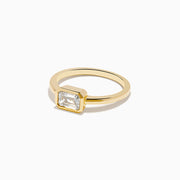 The Lab Grown Diamond East West Emerald-Cut Ring in 14K Yellow Gold features a lab diamond in a minimalist bezel setting, beautifully crafted and shown against a plain white background.