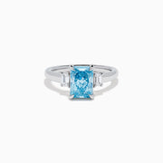The Lab Grown Blue Diamond 3-Stone Ring in 14K White Gold features a brilliant blue center diamond with two clear rectangular side stones, set in sleek white gold against a crisp white background.