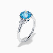 The Lab Grown Blue and White Diamond 3 Stone Ring in 14K White Gold features a striking round blue gemstone center with two rectangular lab grown diamonds on each side, all set in elegant white gold.