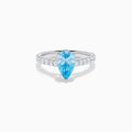 The Lab Grown Blue Diamond Solitaire Pear Ring in 14K White Gold features a striking pear-shaped blue diamond at the center, accented by a band adorned with small round white diamonds.