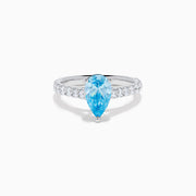 The Lab Grown Blue Diamond Solitaire Pear Ring in 14K White Gold features a striking pear-shaped blue diamond at the center, accented by a band adorned with small round white diamonds.