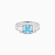 A Lab Grown Blue and White Diamond 3 Stone Ring in 14K White Gold showcases a central rectangular blue diamond flanked by two clear rectangular diamonds, set in gleaming white gold and displayed against a white background.