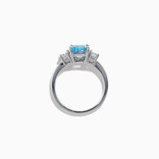 A Lab Grown Blue and White Diamond 3 Stone Ring in 14K White Gold showcases a central rectangular blue diamond flanked by two clear rectangular diamonds, set in gleaming white gold and displayed against a white background.
