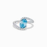 The Lab Grown Blue and White Diamond Connect Ring in 14K White Gold features an oval blue gemstone center, accented with lab grown diamonds on a curved band, shown against a plain white background.