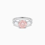 The Lab Grown Pink and White Diamond 3 Stone Ring in 14K White Gold features a striking round pink center stone with two rectangular white diamonds on each side, set against a white background.