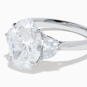 The Lab Grown Oval Diamond 3 Stone Ring in 14K White Gold features a striking lab grown oval diamond center, accented by two pear-shaped diamonds on each side.