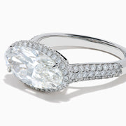 The Lab Grown Diamond East-West Oval Halo Ring in 14K White Gold showcases a brilliant lab-grown diamond center, accented by sparkling stones along the band, beautifully set against a plain white background.