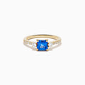 The 14K Yellow Gold Tanzanite and Diamond Ring showcases a square-cut blue tanzanite centerpiece, accented by round white diamonds set along the band.