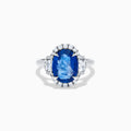 The Effy Hematian 18K White Gold Blue Sapphire and Diamond Halo Ring features a striking oval blue sapphire center, surrounded by round and rectangular diamonds, showcased on a plain white background.