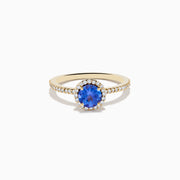 The Nahla 14K Yellow Gold Tanzanite and Diamond Ring showcases a round tanzanite center, encircled by a halo of clear diamonds and accented with additional diamonds along the band.