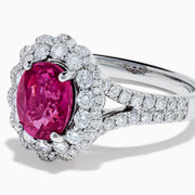 The 18K White Gold Pink Sapphire and Diamond Halo Ring features an oval pink sapphire surrounded by a diamond halo, with additional diamonds along the band for extra sparkle.