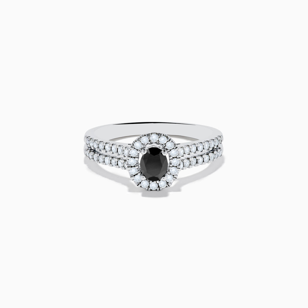 The 14K White Gold White and Black Diamond Halo Ring features an oval black center stone, a halo of white diamonds, and additional diamonds set along its split shank band.