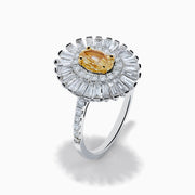 The Canare 18K Two Tone Gold Yellow and White Diamond Ring features an oval yellow centerpiece with a starburst halo of round and baguette white diamonds on a slim, diamond-studded band.