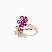 The Nature 14k Rose Gold Pink and White Sapphire Flower Diamond ring features two floral designs—one with pink sapphire petals, the other with white sapphires—set on a curved, stone-adorned band, shown against a white background.