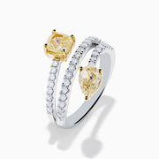 The Canare 18K Two Tone White and Yellow Diamond Bypass Ring features a spiral design with a row of small white diamonds, highlighted by yellow cushion-cut and pear-shaped diamonds set in yellow gold prongs.