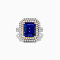 The Nahla Siri 14K Two Tone Gold Tanzanite and Diamond Ring features a rectangular tanzanite with a double halo of white and yellow diamonds, set in a two-tone gold band, shown against a white background.