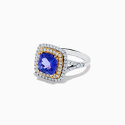 The Nahla Siri 14K Two Tone Gold Tanzanite and Diamond Ring features a large cushion-cut tanzanite center, encircled by a halo of yellow stones and an outer halo of sparkling diamonds.