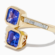 The Nahla 14K Yellow Gold Tanzanite and Diamond Bypass Ring features two square-cut tanzanites on each end of an open band, accented with small rectangular diamonds along the yellow gold band.