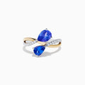 The Nahla 14K Two Tone Gold Tanzanite and Diamond Bypass Ring features two pear-shaped tanzanites and a curved band with sparkling white diamonds, displayed against a white background.