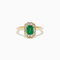 The 14K Yellow Gold Emerald and Diamond Halo Vintage Ring features an emerald-cut green center stone, accented by round and baguette white diamonds in a vintage halo setting.