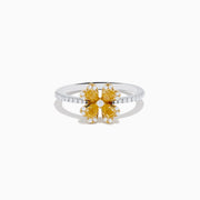 The Canare 14K White & Yellow Gold Yellow Diamond Flower Ring features a four-petal design with yellow diamonds and a central clear stone, set on a slim band accented with small white stones.