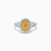 The Canare 18K Two Tone Gold White and Yellow Oval Diamond Split Shank Ring showcases an oval yellow diamond center with a double halo of white diamonds and a diamond-accented split shank, displayed on a plain white background.