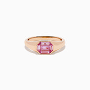 The 14K Rose Gold Bezel Set Pink Sapphire Ring showcases an emerald-cut pink sapphire in a bezel setting, presented on a white background.
