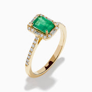 The 14K Yellow Gold Emerald and Diamond Ring showcases a rectangular emerald center stone, accented by white diamonds around the gemstone and along the band.