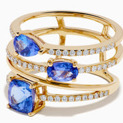 The 14K Yellow Gold Tanzanite and Diamond Multi-Row Statement Ring features three stacked bands set with white diamonds and pear, oval, and cushion-cut blue tanzanite gemstones.