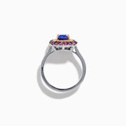 The 14K Two Tone Gold Tanzanite, Diamond, and Pink Sapphire Cushion Halo Ring features a striking tanzanite center, framed by sparkling diamonds and a halo of vivid pink sapphires on a sleek white background.