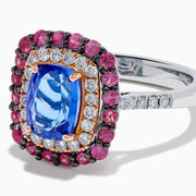 The 14K Two Tone Gold Tanzanite, Diamond, and Pink Sapphire Cushion Halo Ring features a striking tanzanite center, framed by sparkling diamonds and a halo of vivid pink sapphires on a sleek white background.