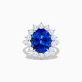 The Hematian 14K White Gold Tanzanite and Diamond Ring showcases a striking oval blue tanzanite center with a halo of round white diamonds, displayed on a plain white background.