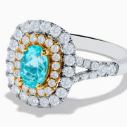 The 18K Two Tone Gold Paraiba and Diamond Double Halo Ring features an oval Paraiba centerpiece, surrounded by radiant yellow and white diamonds in a double halo, creating a striking layered effect.