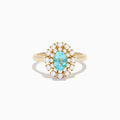 The 18K Yellow Gold Paraiba and Diamond Ring features an oval Paraiba gemstone at the center, encircled by a double halo of round diamonds, all showcased on a plain white background.