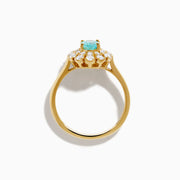 The 18K Yellow Gold Paraiba and Diamond Ring features an oval Paraiba gemstone at the center, encircled by a double halo of round diamonds, all showcased on a plain white background.