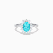 The 14K White Gold Paraiba and Diamond Halo Ring showcases an oval-shaped Paraiba gemstone at the center, encircled by a sparkling diamond halo with additional diamonds adorning the band.