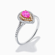 The 14K Two Tone Gold Pink Sapphire and Diamond Halo Ring showcases a pear-shaped pink sapphire center, double diamond halo with gold accents, and extra diamonds set along its two tone gold band.