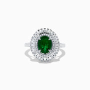 The 14K White Gold Emerald and Diamond Ring features an oval emerald center accented by two rows of baguette and round diamonds in a radiant halo design.