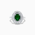 The 14K White Gold Emerald and Diamond Ring features an oval emerald center accented by two rows of baguette and round diamonds in a radiant halo design.