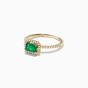 The 14K Yellow Gold Emerald and Diamond Ring features a square-cut emerald center, a halo of white diamonds, and a twisted band design.