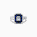 The Royale Bleu 14K White Gold Blue Sapphire and Diamond Ring showcases a rectangular center diamond, encircled by a blue sapphire halo, a second white diamond halo, and baguette-cut diamonds on the band.