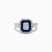 The Royale Bleu 14K White Gold Blue Sapphire and Diamond Ring showcases a rectangular center diamond, encircled by a blue sapphire halo, a second white diamond halo, and baguette-cut diamonds on the band.