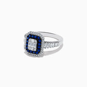 The Royale Bleu 14K White Gold Blue Sapphire and Diamond Ring showcases a rectangular center diamond, encircled by a blue sapphire halo, a second white diamond halo, and baguette-cut diamonds on the band.