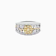 This 14K two tone gold flower ring features a wide band with a central cluster of yellow diamonds, surrounded by small white diamonds, and elegant gold and silver accents.