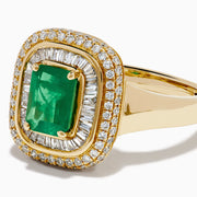 The 14K Yellow Gold Emerald and Diamond Double Halo Ring features an emerald-cut green gemstone at the center, framed by two rows of round and baguette diamonds in a rectangular halo setting.