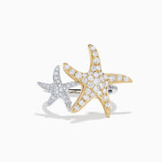 The 18K Two Tone Gold Diamond Double Starfish Ring features overlapping gold and silver starfish set with sparkling diamonds on a sleek silver band, creating a striking two-tone look against a white background.