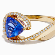 The 14K Yellow Gold Trillion Tanzanite and Diamond Swirl Ring showcases a triangular blue tanzanite center framed by a swirl of white diamonds, all set against a plain white background.